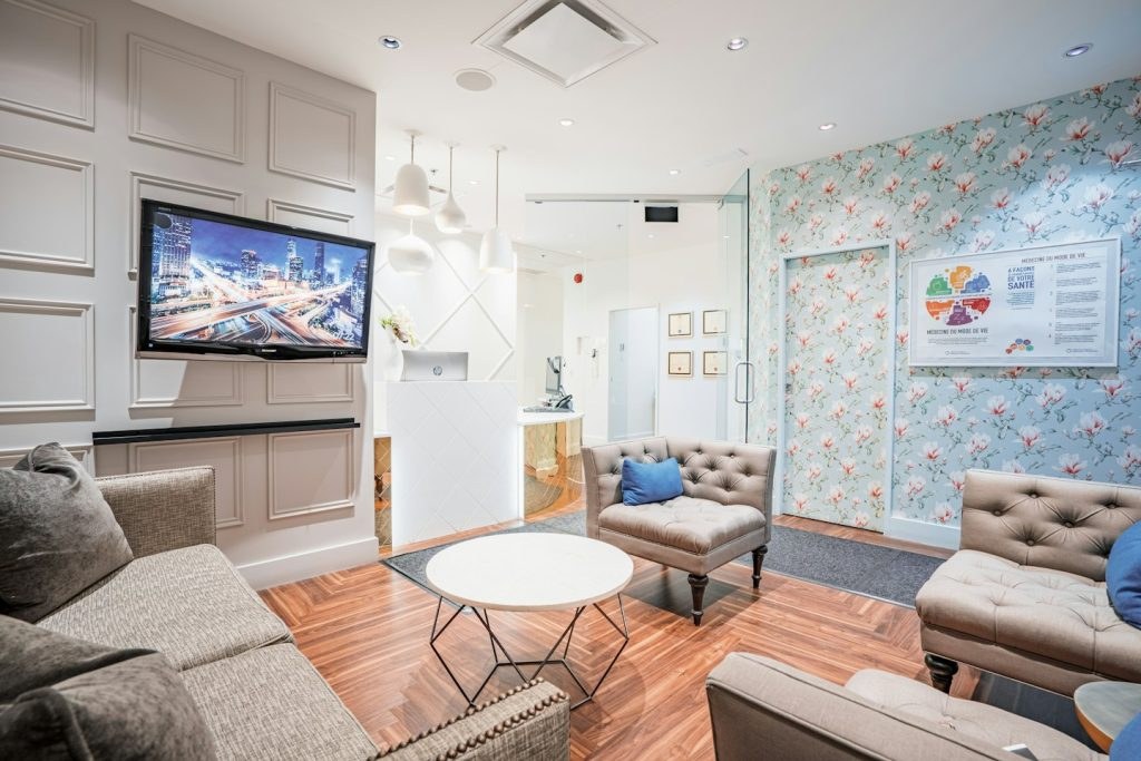 Modern waiting area with sofas, a reception desk, and floral wallpaper