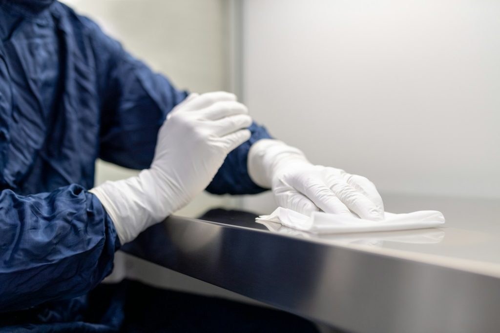 Person in a blue suit wiping down a counter with a cloth
