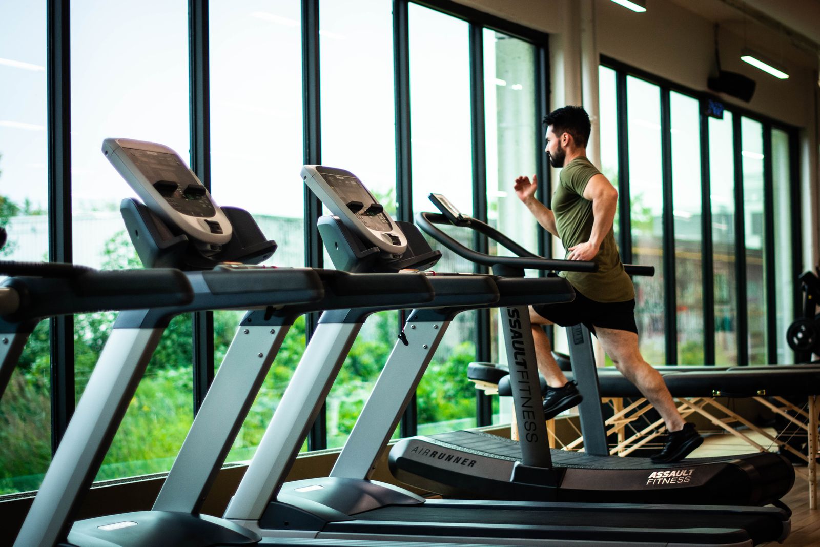 Row of treadmills in a bright gym with a man running