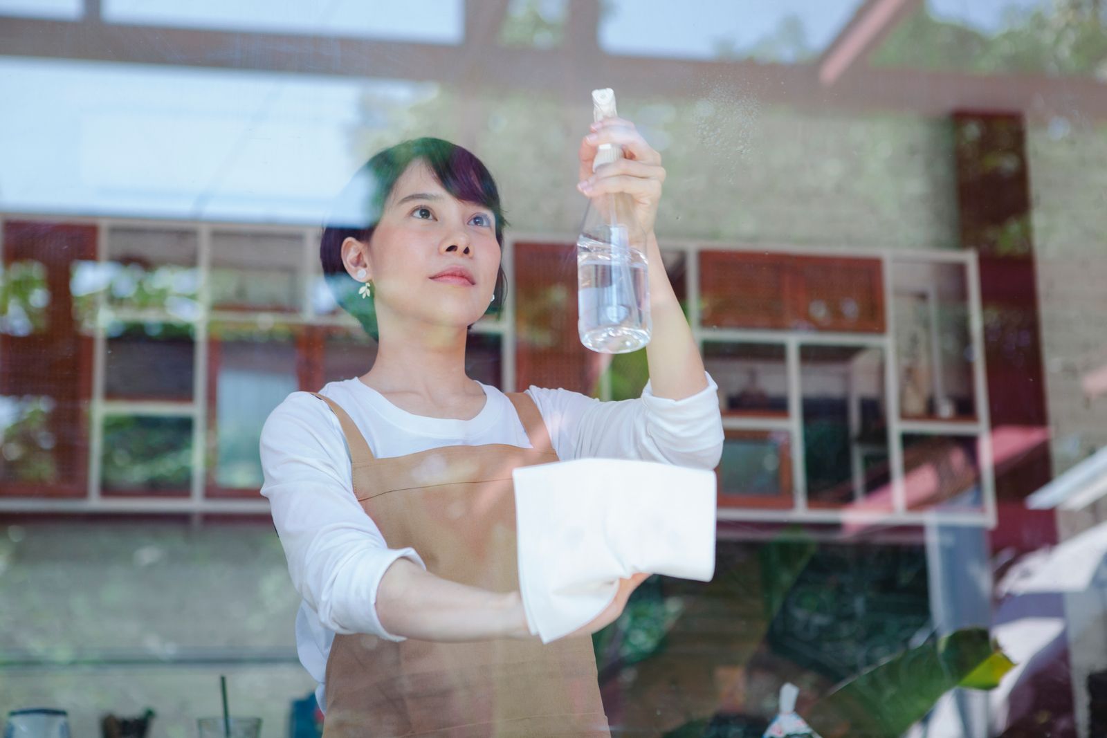 Woman wiping glass with a spray bottle and cloth in a restaurant